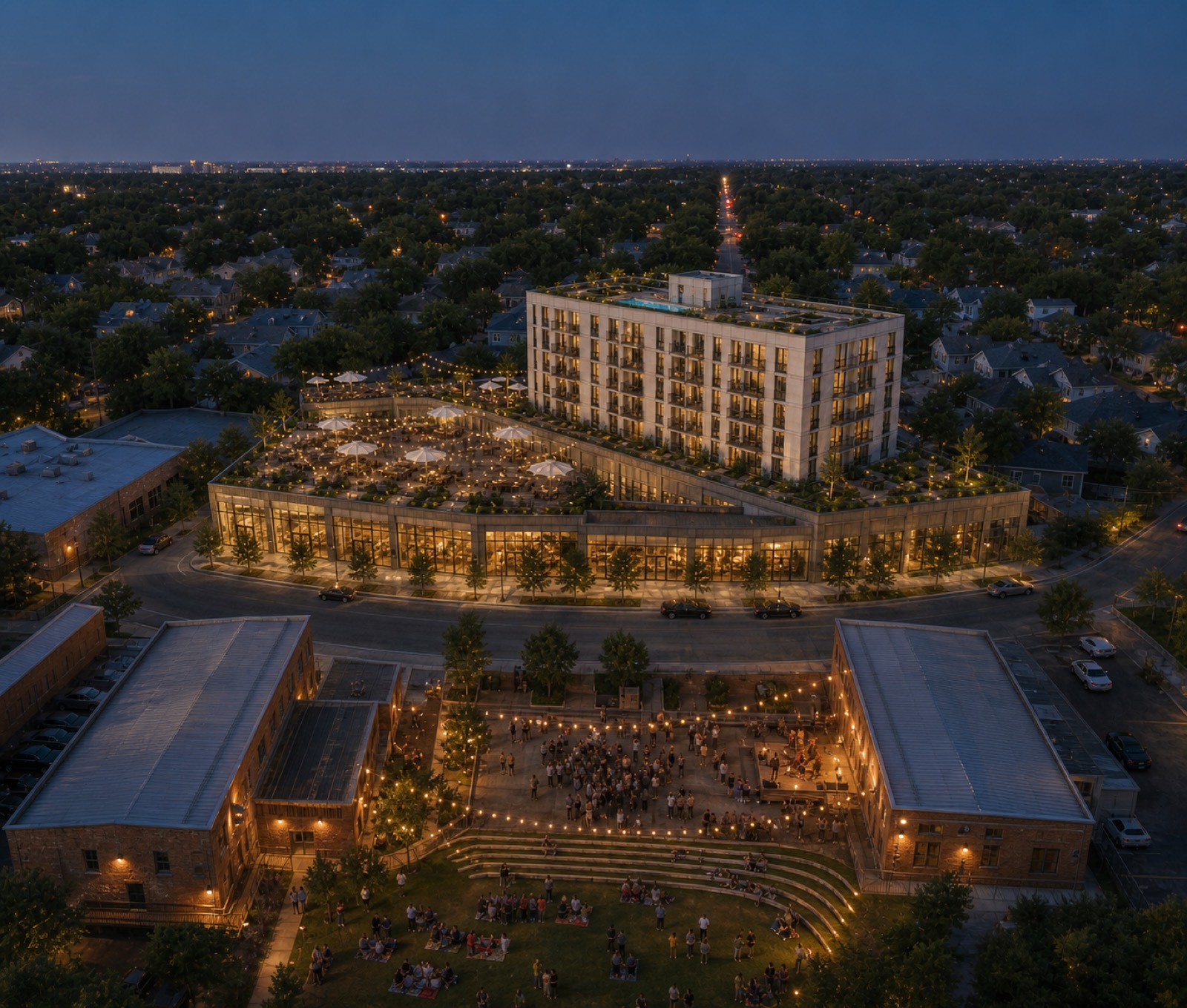 Dusk aerial from above the music venue looking north: the venue lawn and crowd in the foreground, the brewery event terrace and residential bar glowing beyond
